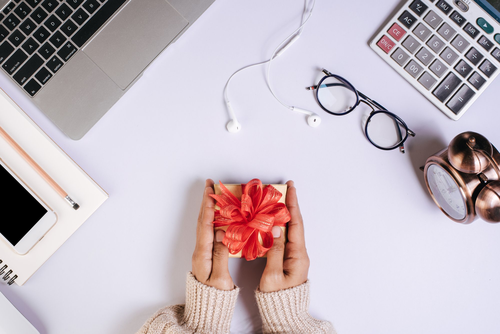 vista-superior-de-la-mano-con-caja-de-regalo-en-el-espacio-de-trabajo